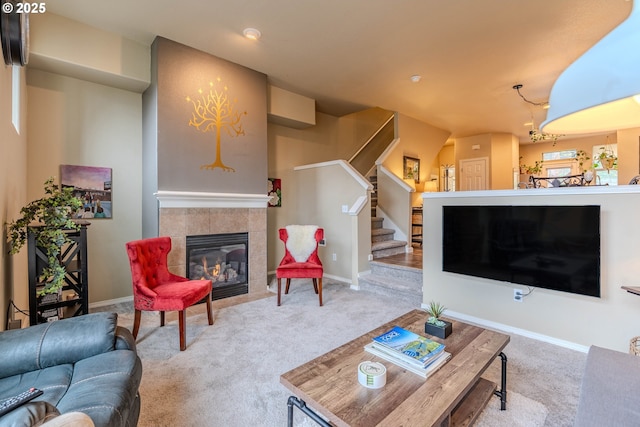 carpeted living room with baseboards, a tiled fireplace, and stairs