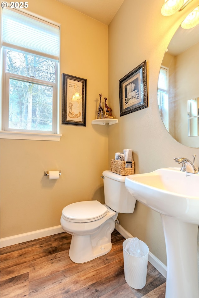 half bathroom featuring baseboards, toilet, and wood finished floors