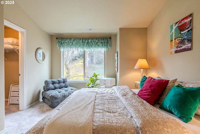 bedroom featuring baseboards, a spacious closet, visible vents, and carpet flooring