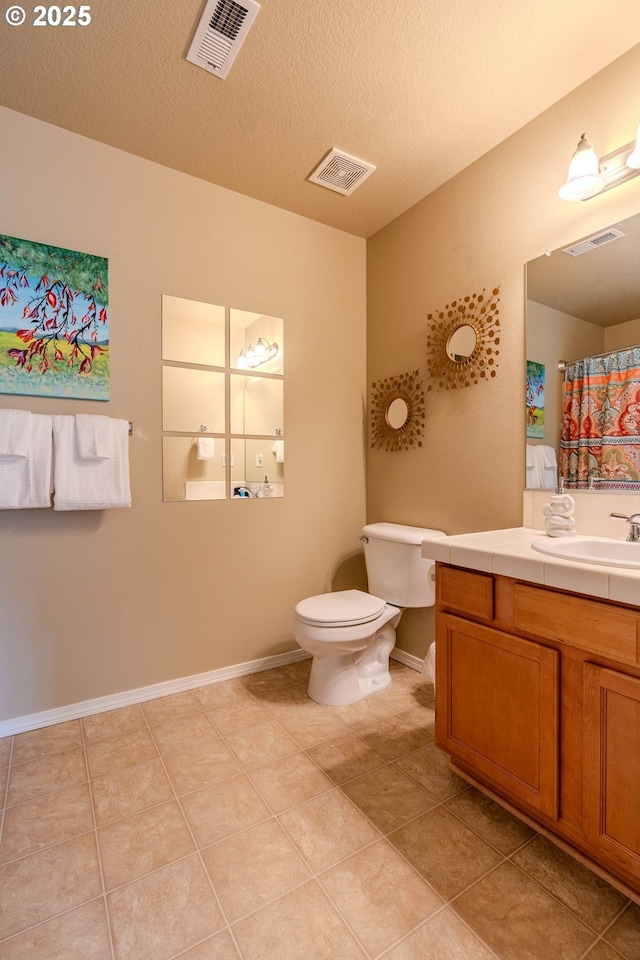 bathroom with toilet, vanity, and visible vents