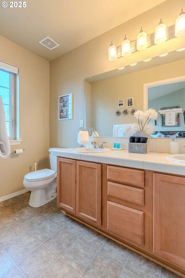 full bath featuring toilet, double vanity, a sink, and visible vents