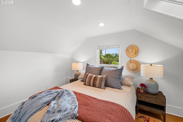 bedroom with vaulted ceiling, wood finished floors, and baseboards