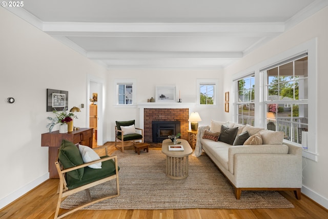 living area featuring beamed ceiling, wood finished floors, a brick fireplace, and baseboards