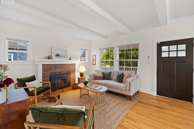 living area with light wood-type flooring, beamed ceiling, a fireplace, and baseboards
