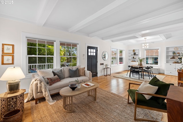 living area with a chandelier, light wood-style floors, beam ceiling, baseboards, and built in features