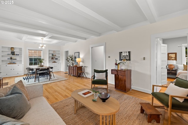 living room featuring a chandelier, beamed ceiling, light wood-type flooring, built in shelves, and baseboards