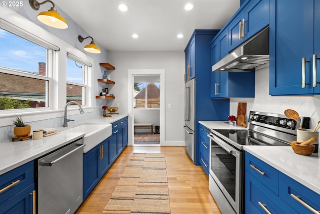 kitchen with stainless steel appliances, under cabinet range hood, blue cabinetry, recessed lighting, and backsplash