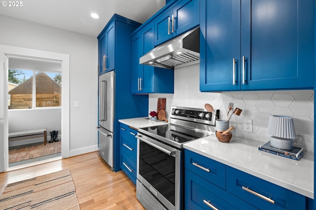 kitchen featuring stainless steel appliances, under cabinet range hood, blue cabinetry, light countertops, and light wood-style flooring