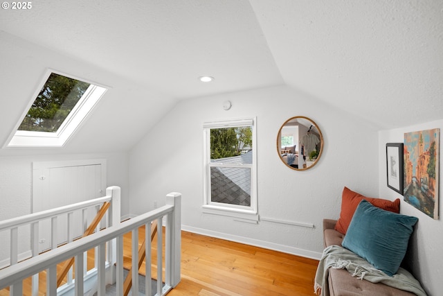 additional living space featuring a skylight, lofted ceiling, light wood-type flooring, and baseboards