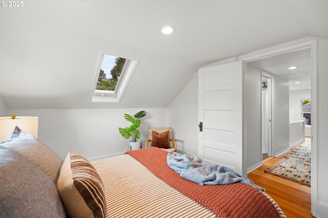 bedroom with a skylight, vaulted ceiling, wood finished floors, recessed lighting, and baseboards