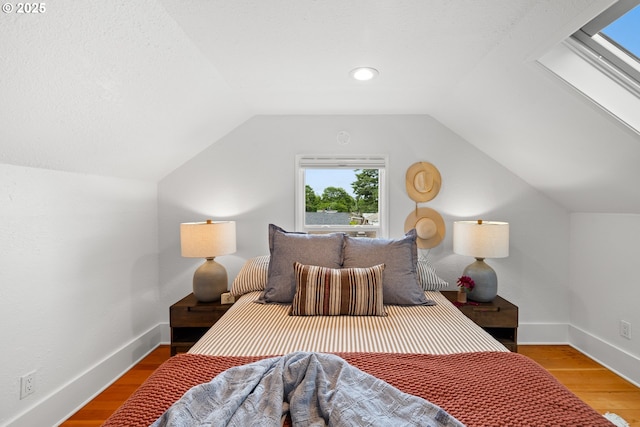 bedroom featuring lofted ceiling, wood finished floors, and baseboards