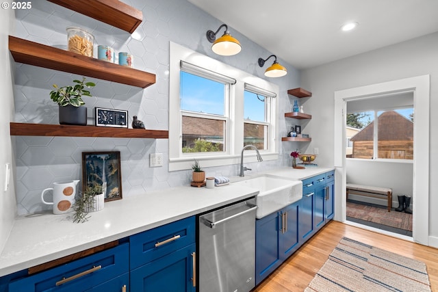 kitchen with open shelves, stainless steel dishwasher, blue cabinetry, a sink, and recessed lighting