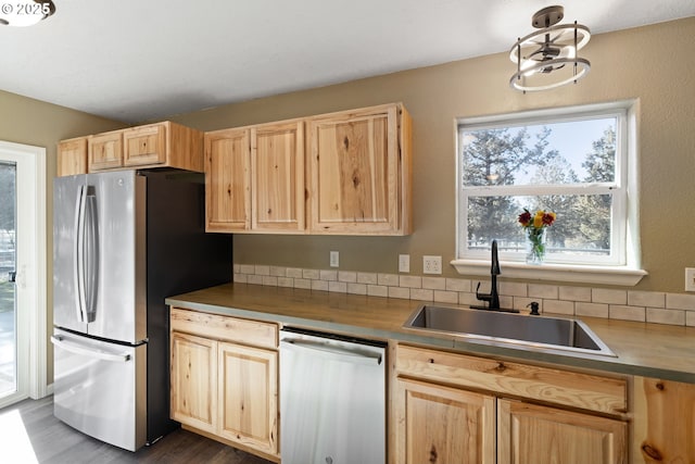 kitchen featuring appliances with stainless steel finishes, a sink, and light brown cabinetry