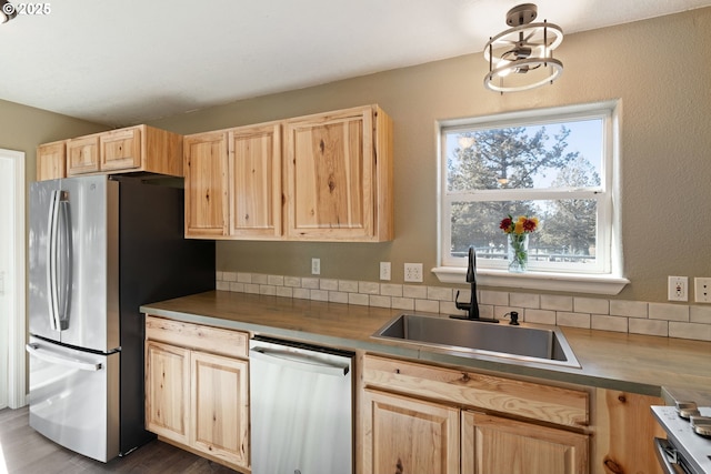 kitchen featuring light brown cabinetry, dark countertops, a sink, and stainless steel appliances