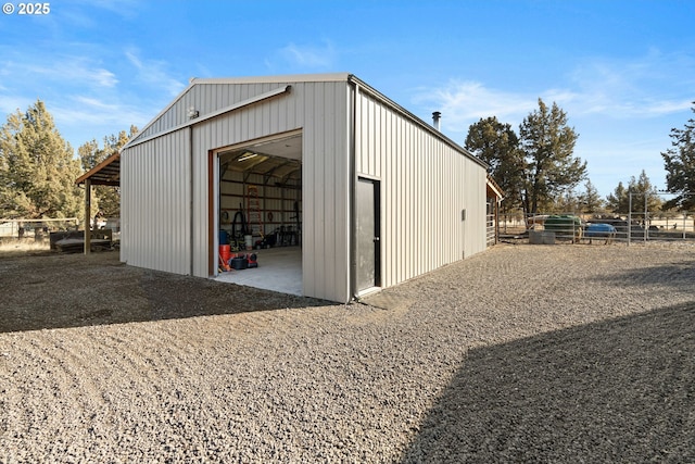 view of pole building featuring gravel driveway and fence