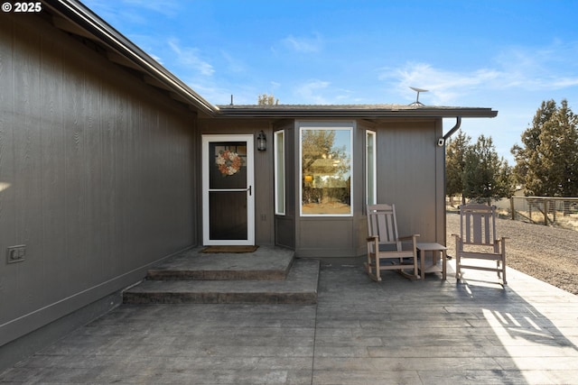 entrance to property featuring fence and a patio