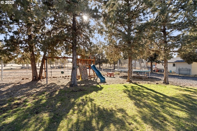 view of yard with a trampoline, a playground, and fence