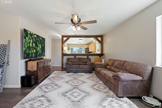 living area with ceiling fan, baseboards, and dark wood-style flooring