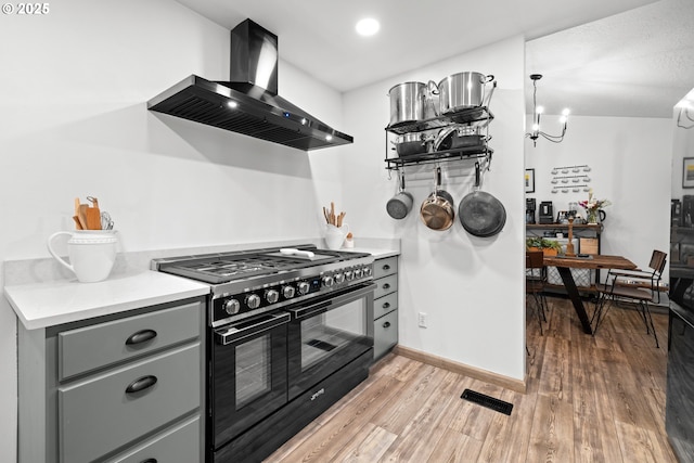14370 SW Wilson Dr, Beaverton, OR 97008 - kitchen featuring high end black range oven, wall chimney exhaust hood, gray cabinets, light wood finished floors, and light countertops