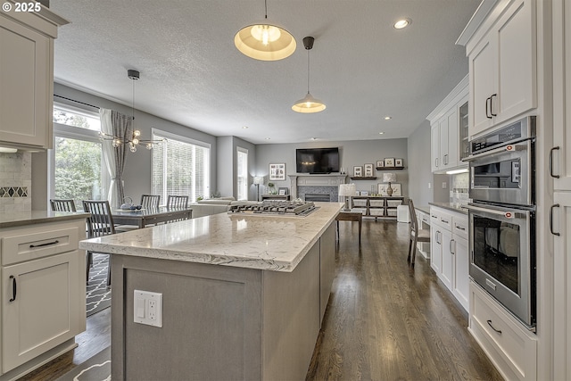 15178 NW Channa Dr, Portland, OR 97229 - kitchen featuring a chandelier, a fireplace, dark wood-style floors, backsplash, and open floor plan