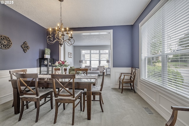 15178 NW Channa Dr, Portland, OR 97229 - dining area with a textured ceiling, a chandelier, wainscoting, a decorative wall, and light carpet