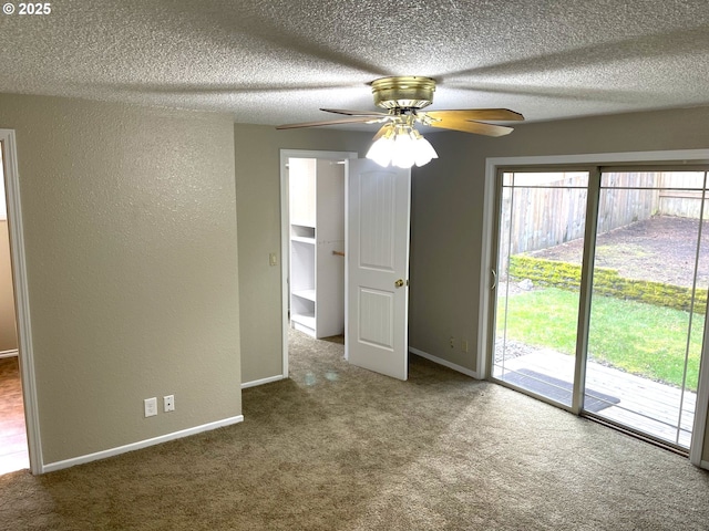 carpeted empty room featuring baseboards, a wealth of natural light, and a textured wall