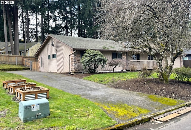 ranch-style home featuring a front yard, stone siding, and fence