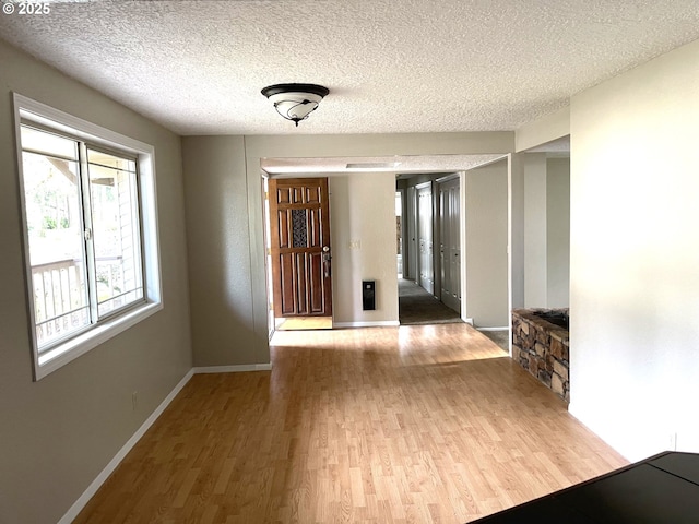 corridor with a textured ceiling, wood finished floors, and baseboards