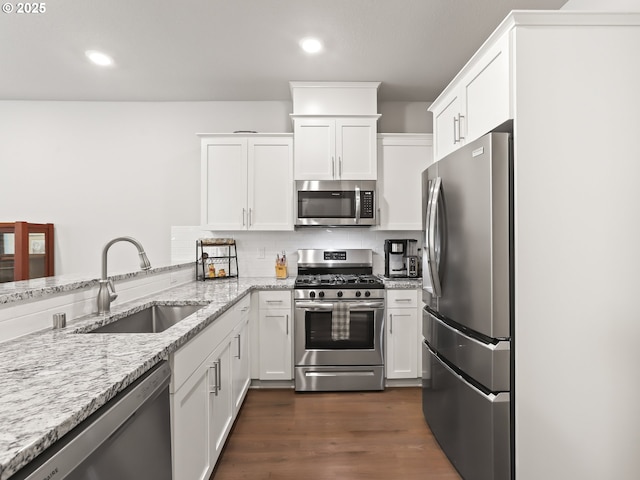 2421 S Trail View Ct, Ridgefield, WA 98642 - kitchen with white cabinetry, light stone counters, a sink, backsplash, and stainless steel appliances
