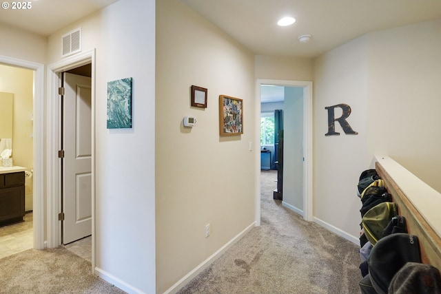 hall with baseboards, visible vents, recessed lighting, and light colored carpet