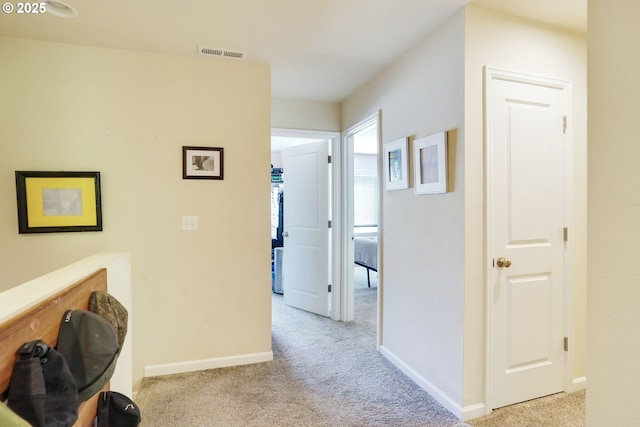 hallway featuring visible vents, carpet flooring, and baseboards