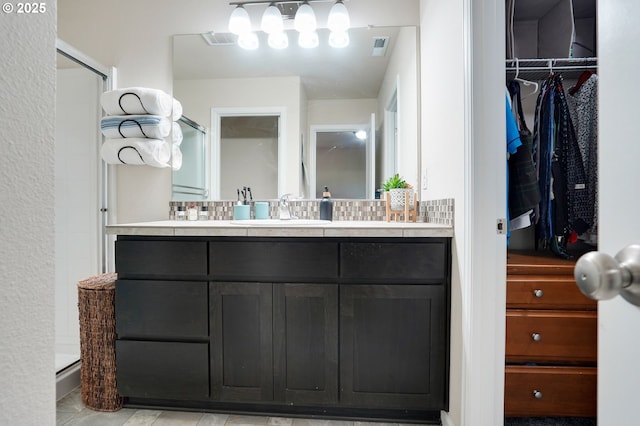 full bathroom with visible vents, a shower stall, a spacious closet, and vanity