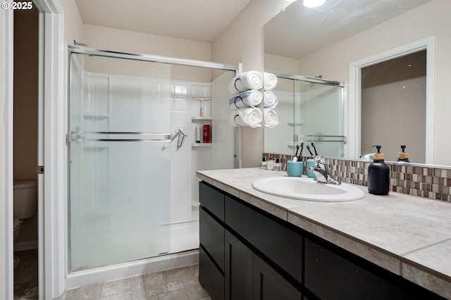full bath featuring vanity, toilet, a shower stall, and tasteful backsplash