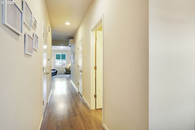 hall featuring baseboards, a wall mounted AC, recessed lighting, and wood finished floors