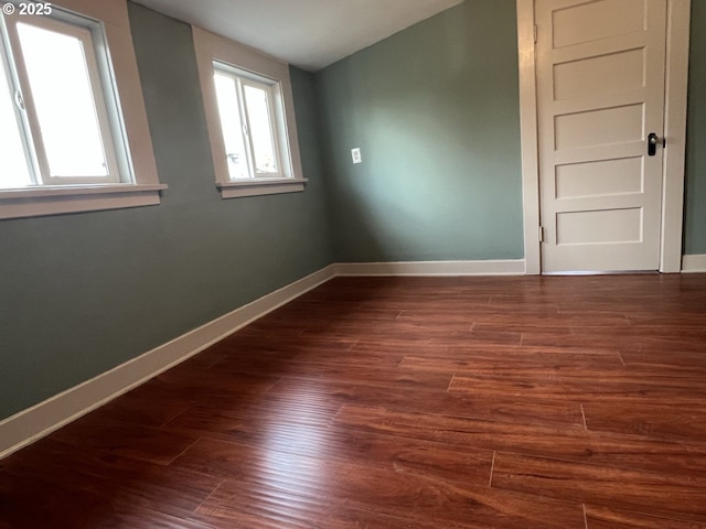 unfurnished room with a wealth of natural light, dark wood-style floors, and baseboards
