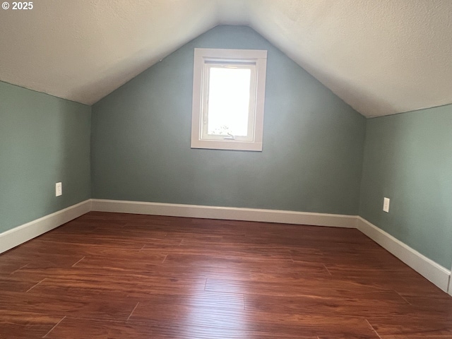 additional living space with baseboards, wood finished floors, and lofted ceiling