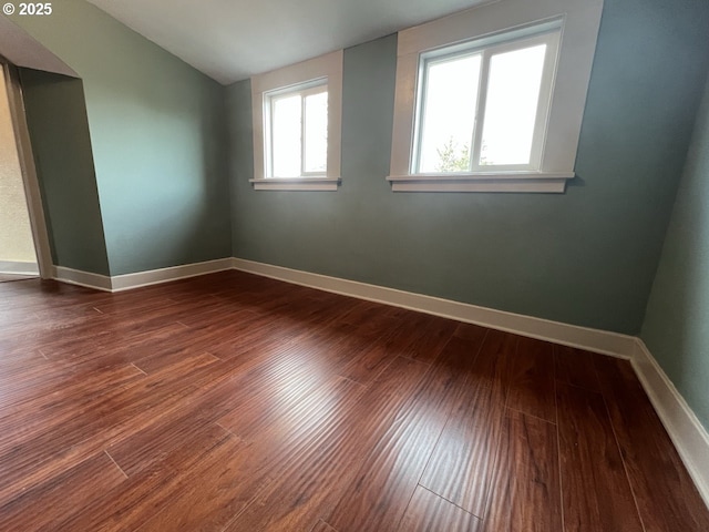 unfurnished room featuring vaulted ceiling, dark wood finished floors, and baseboards