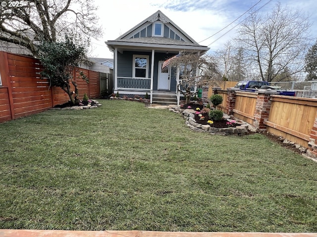 back of house with a fenced backyard, covered porch, and a lawn