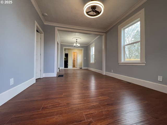 unfurnished dining area featuring a chandelier, crown molding, baseboards, and dark wood finished floors