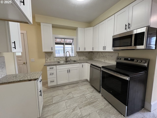 kitchen with electric range, dishwasher, stainless steel microwave, white cabinetry, and a sink