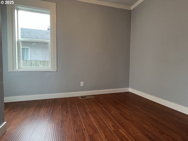 unfurnished room with ornamental molding, dark wood-style flooring, visible vents, and baseboards