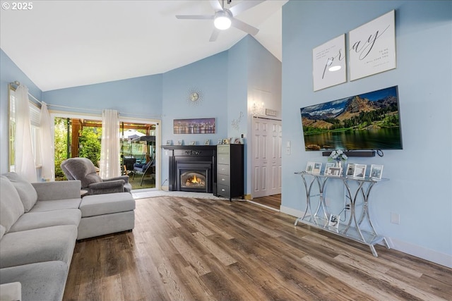 1650 NW Lakeway Ln, Beaverton, OR 97006 - living area with high vaulted ceiling, wood finished floors, a ceiling fan, a lit fireplace, and baseboards