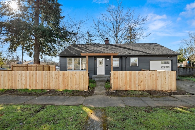 view of front of property featuring a fenced front yard, a chimney, and a garage