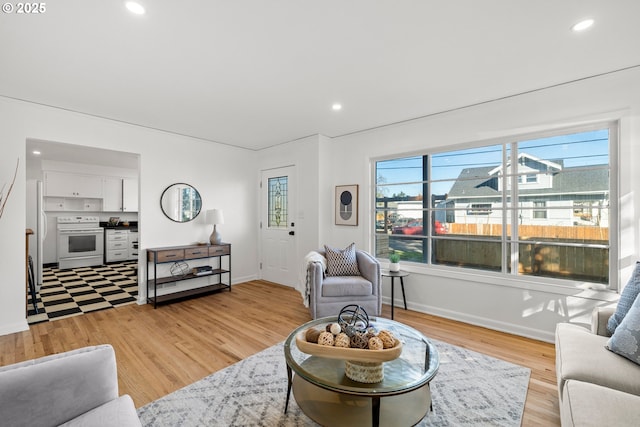 living area with baseboards, light wood finished floors, and recessed lighting