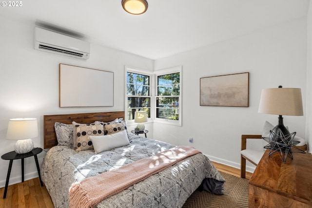 bedroom featuring baseboards, wood finished floors, and a wall mounted air conditioner