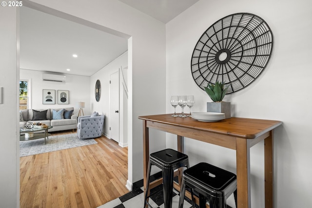 interior space featuring a wall unit AC, baseboards, wood finished floors, and recessed lighting