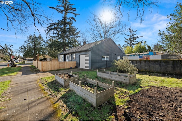 view of property exterior with a vegetable garden, driveway, and fence