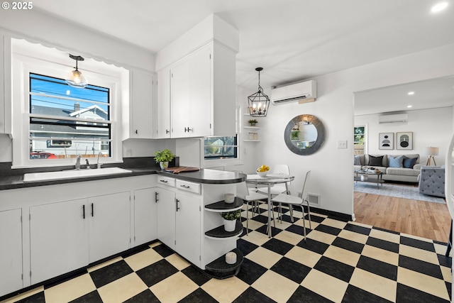 kitchen featuring light floors, a wall mounted AC, dark countertops, and a sink