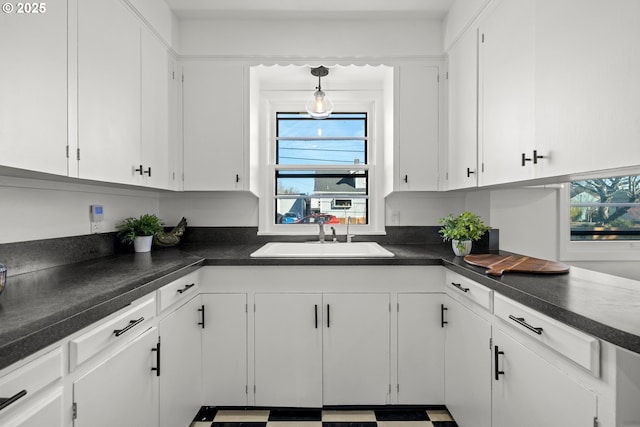 kitchen featuring dark countertops, white cabinets, and a sink