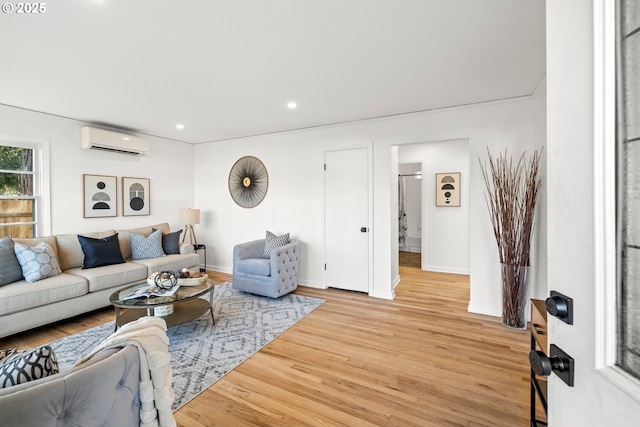 living room featuring light wood-type flooring, a wall unit AC, baseboards, and recessed lighting